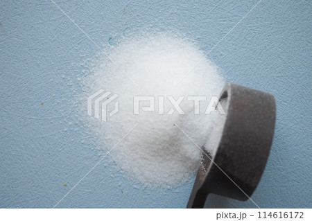 top view of white salt and a wooden spoon on a light blue background  114616172