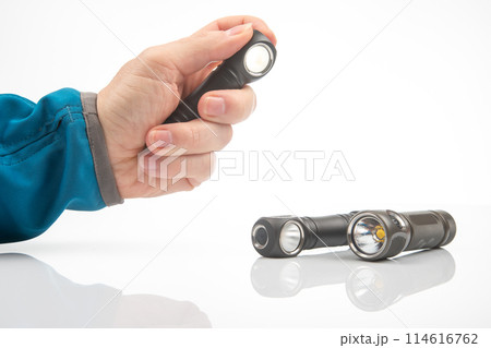 hand holds a flashlight against the background of other flashlights on a white background. 114616762