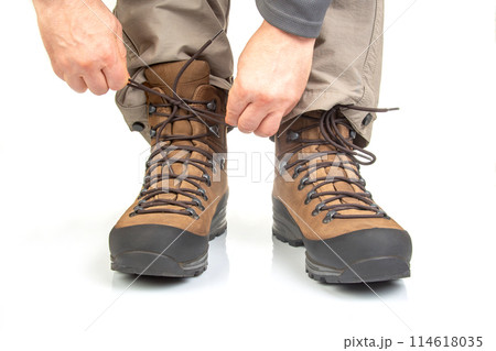 Trekking boots for hiking on the legs of a tourist on a white background 114618035
