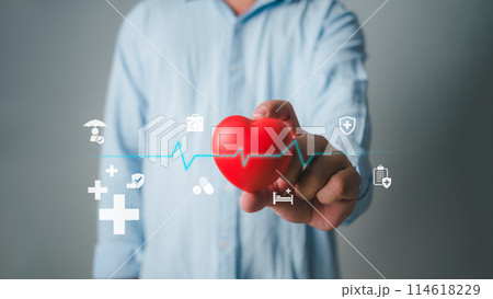 Man holding heart shape toy and while standing against grey background, Cardiology, Heart in left hand, health planning, Insurance healthcare and medical concept, Heart health insurance. Man holding heart shape toy and while standing against grey background, Cardiology, Heart in left hand, health planning, Insurance healthcare and medical concept, Heart health insurance. 114618229
