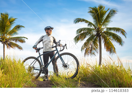 bearded male cyclist in yellow clothes on a bicycle against the background of palm trees 114618383