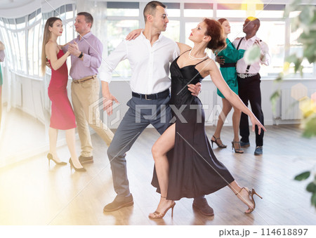 Dance training in group - men and women of different nationalities and different ages dance tango or bachata in dance studio 114618897