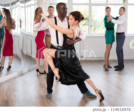 Dance training in group - men and women of different nationalities and different ages dance tango or bachata in dance studio 114618978