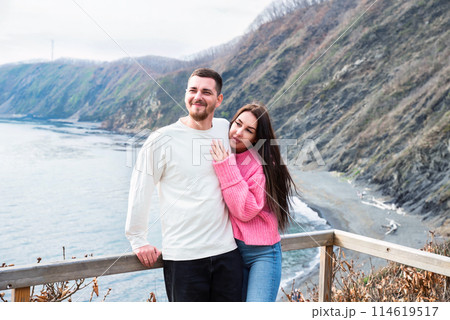 Young married couple hugging together and standing against japanese sea Young married couple hugging together and standing against japanese sea 114619517
