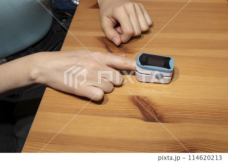 Person Uses Pulse Oximeter Measuring Oxygen Saturation In Blood And Heart Rate. Pulse Oximeter On The Woman's Hand. Healthcare, Disease Prevention. Horizontal Plane 114620213