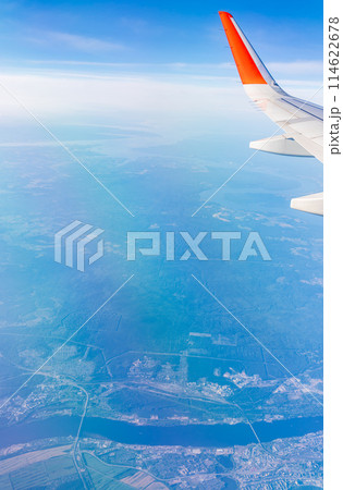 Aerial view from airplane window above green ground. View from the airplane window with beautiful clouds at sunrise Aerial view from airplane window above green ground. View from the airplane window with beautiful clouds at sunrise 114622678