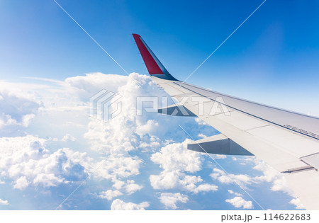 View from the airplane window at a beautiful cloudy sky and the airplane wing View from the airplane window at a beautiful cloudy sky and the airplane wing 114622683