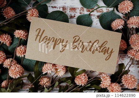 Happy Birthday text message on paper card with flowers border frame on wooden background Happy Birthday text message on paper card with flowers border frame on wooden background 114622890