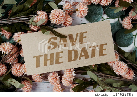 Save the Date text message on paper card with flowers border frame on wooden background Save the Date text message on paper card with flowers border frame on wooden background 114622895