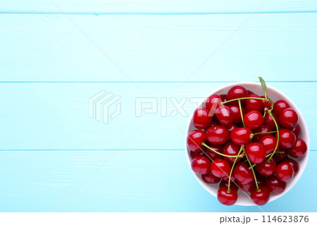 Fresh red cherry fruit in plate on blue wooden table Fresh red cherry fruit in plate on blue wooden table 114623876