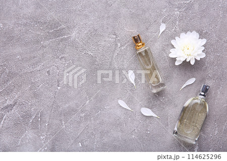 Perfume bottles with flowers on grey concrete background Perfume bottles with flowers on grey concrete background 114625296