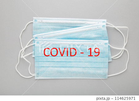 Medical masks on a grey background with copy space. The inscription Covid 19 Medical masks on a grey background with copy space. The inscription Covid 19 114625971