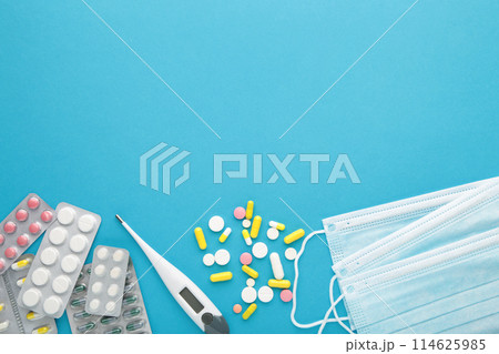 Medical thermometer and mask with pills on blue. Medical concept 114625985