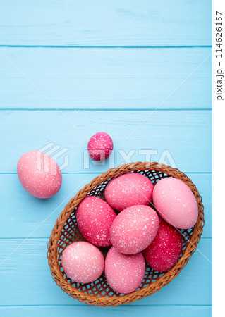 Pink easter eggs in basket on blue wooden background Pink easter eggs in basket on blue wooden background 114626157