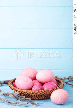 Pink easter eggs in basket and willow branches on blue background 114626164