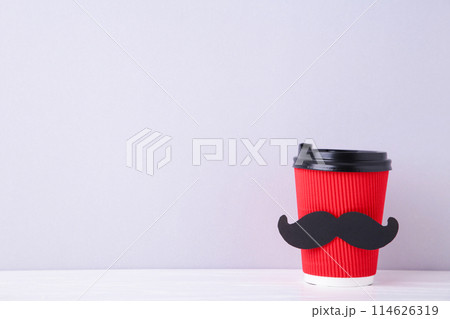 Paper cup of coffee with mustache decoration on grey background, top view. 114626319