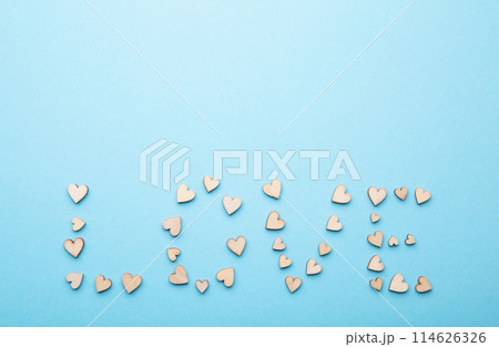 Many small wooden hearts on blue background. Backdrop for wedding cards or Valentine. Top view. Flat lay. 114626326