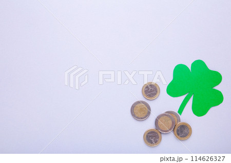 Happy Saint Patrick's of handmade paper clover leaf with coins on grey background. 114626327