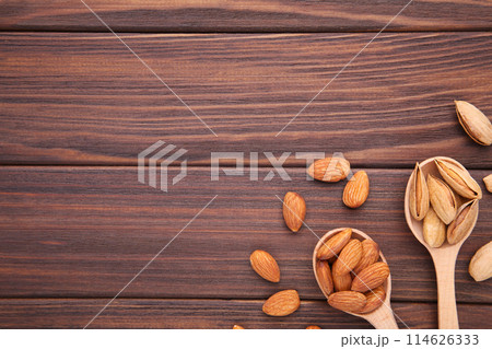 Almonds on wooden spoons on brown wooden background 114626333