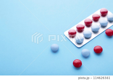 Red and blue tablets on a blue background, top view 114626381
