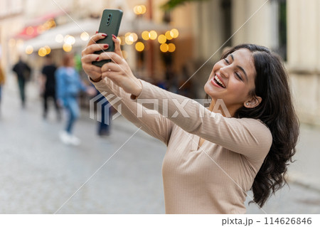 Indian woman blogger taking selfie on smartphone video call online with subscribers on city street Indian woman blogger taking selfie on smartphone video call online with subscribers on city street 114626846