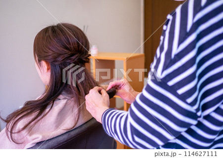 美容院で髪の毛をセットしてもらっている若い女性の後ろ姿 114627111