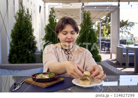 medium sized woman in peach fuzz dress eating Shakshouka in modern restaurant 114627299