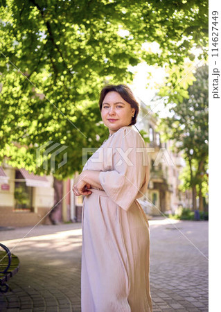 plus size woman in peach fuzz dress dancing on the streets of the morning city 114627449