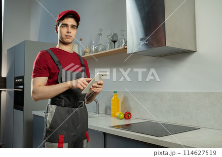 Professional Repairman Fixes Kitchen Range Hood in Modern Home Setting Professional Repairman Fixes Kitchen Range Hood in Modern Home Setting 114627519