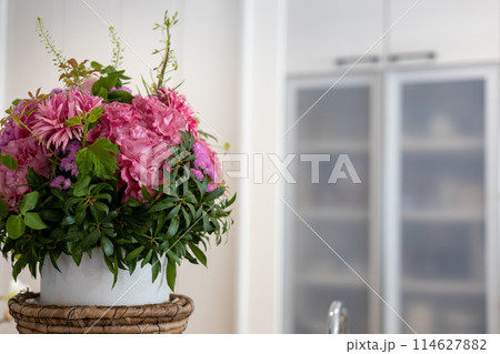 キッチンのカウンターに置いてあるピンクの美しい花のアレンジ 114627882