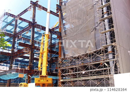 ビル建設工事で鉄骨を作業するクレーン車 114628164