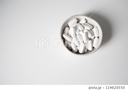 White pills in small bowl on a white background White pills in small bowl on a white background 114628550