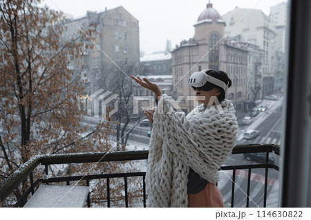 Virtual reality meets the winter city as a girl wears VR glasses against its backdrop. 114630822