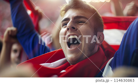 a soccer fan, their eyes shining with passion as they raise their scarf high in the air 114630863