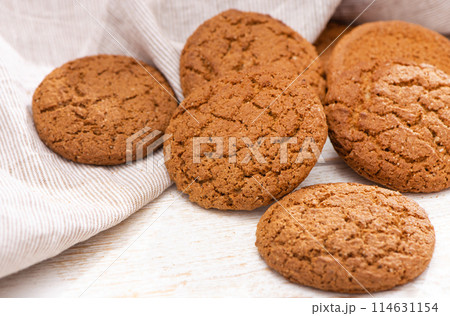 Fresh oatmeal cookies with sugar on a rustic wood table, tea towel. Top view. Homemade baking close up 114631154