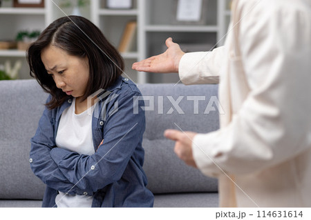 A woman appears upset and stressed while having an argument with her partner at home, conveying emotions of tension and conflict. A woman appears upset and stressed while having an argument with her partner at home, conveying emotions of tension and conflict. 114631614