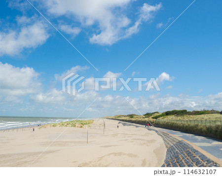 Oostende, Belgium - August 1st 2023: The beach promenade and dunes at the coast close to the city. Oostende, Belgium - August 1st 2023: The beach promenade and dunes at the coast close to the city. 114632107