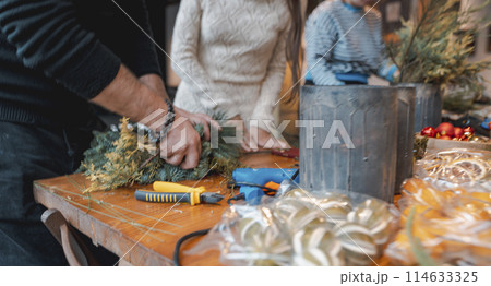 A young lady making a Christmas wreath at a DIY decor session. A young lady making a Christmas wreath at a DIY decor session. 114633325