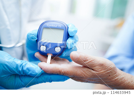 Asian doctor using digital glucose meter for check sample blood sugar level to treatment diabetes. 114633945