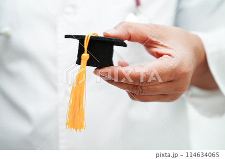 Asian woman doctor holding graduation hat in hospital, Medical education concept. 114634065