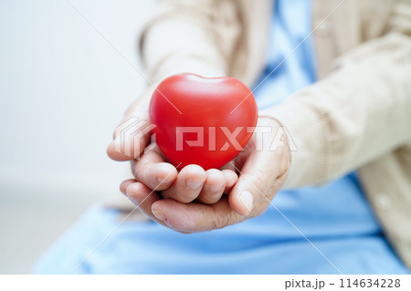 Asian elder senior woman patient holding red heart in hospital. Asian elder senior woman patient holding red heart in hospital. 114634228
