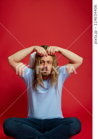 Dad with his daughter's hair draped over his head, creating funny and playful moment against vibrant red background. Dad with his daughter's hair draped over his head, creating funny and playful moment against vibrant red background. 114634406