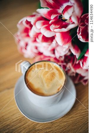 Spring tulips and cup of coffee on wooden table Spring tulips and cup of coffee on wooden table 114634490