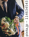 Groom with a bouquet looks at his watch 114634543