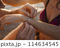 A man puts a bracelet with a heart on a girl's hand 114634545
