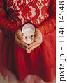woman in red dress holding wedding rings	 114634548
