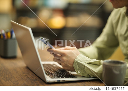 パソコンの前でスマホを使用する若い男性 114637435