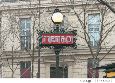 A pole with traditional metro sign under lamp in front of classic european building. A pole with traditional metro sign under lamp in front of classic european building. 114638081