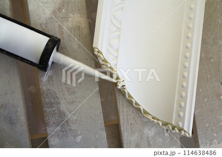 Close-up detail of decoration molding with glue adhesive before installation in interior renovation. 114638486