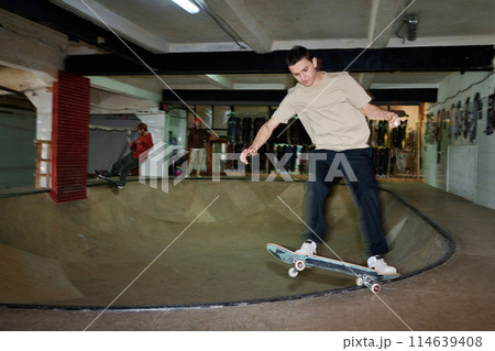 Motion blur wide shot of sporty young man and his friends practicing skateboarding in skatepark, copy space 114639408